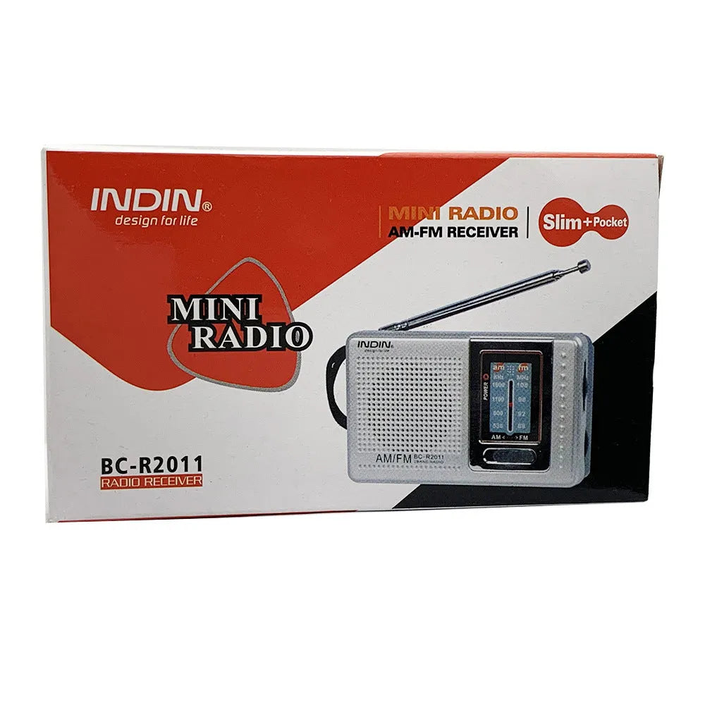 Portable silver grey FM AM radio on table, compact ABS body with built-in speaker and dial controls