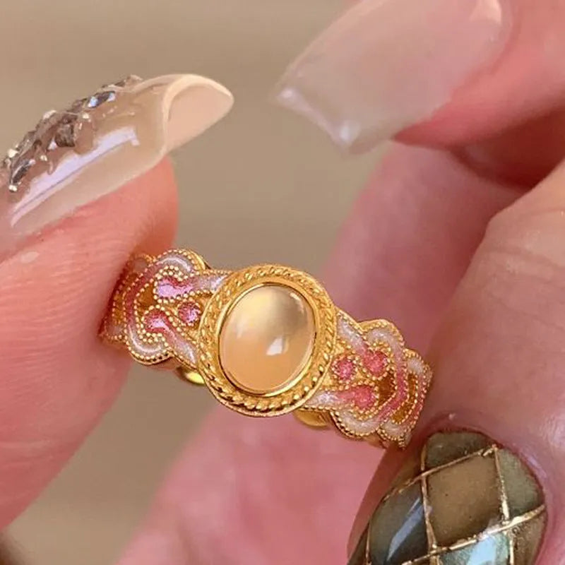Close-up of a women's adjustable open ring with pink crystal enamel on a geometric gold-plated band.