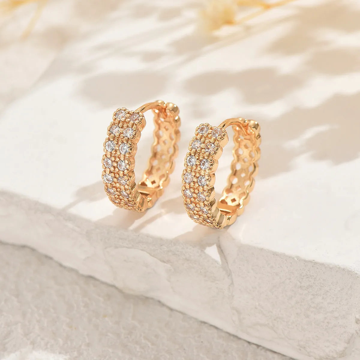 Polished copper geometry pattern ear studs with round base, central dot, and outer ring on a plain background.
