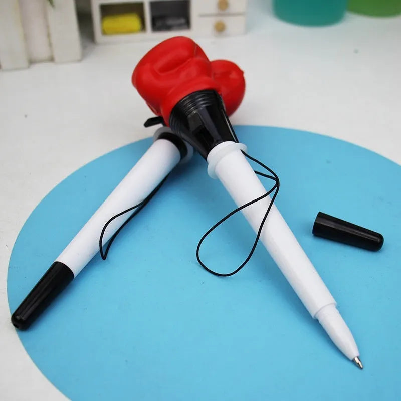Set of four black pressure relief pens with a boxing press ejection mechanism on a desk.