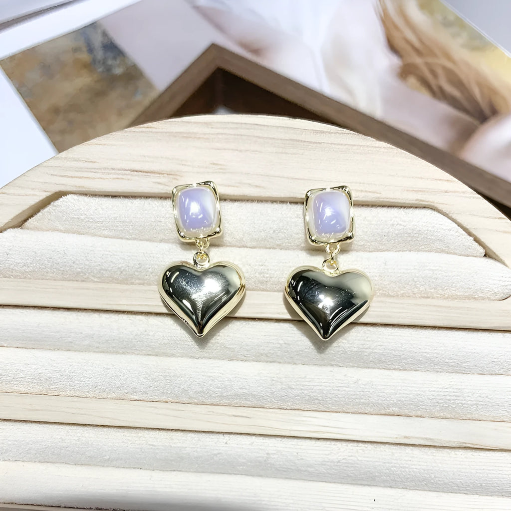 Small gold heart stud earrings with hypoallergenic metal finish on white background