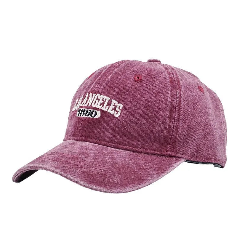 Retro distressed beige cap with adjustable strap and embroidered letters on a conical crown.