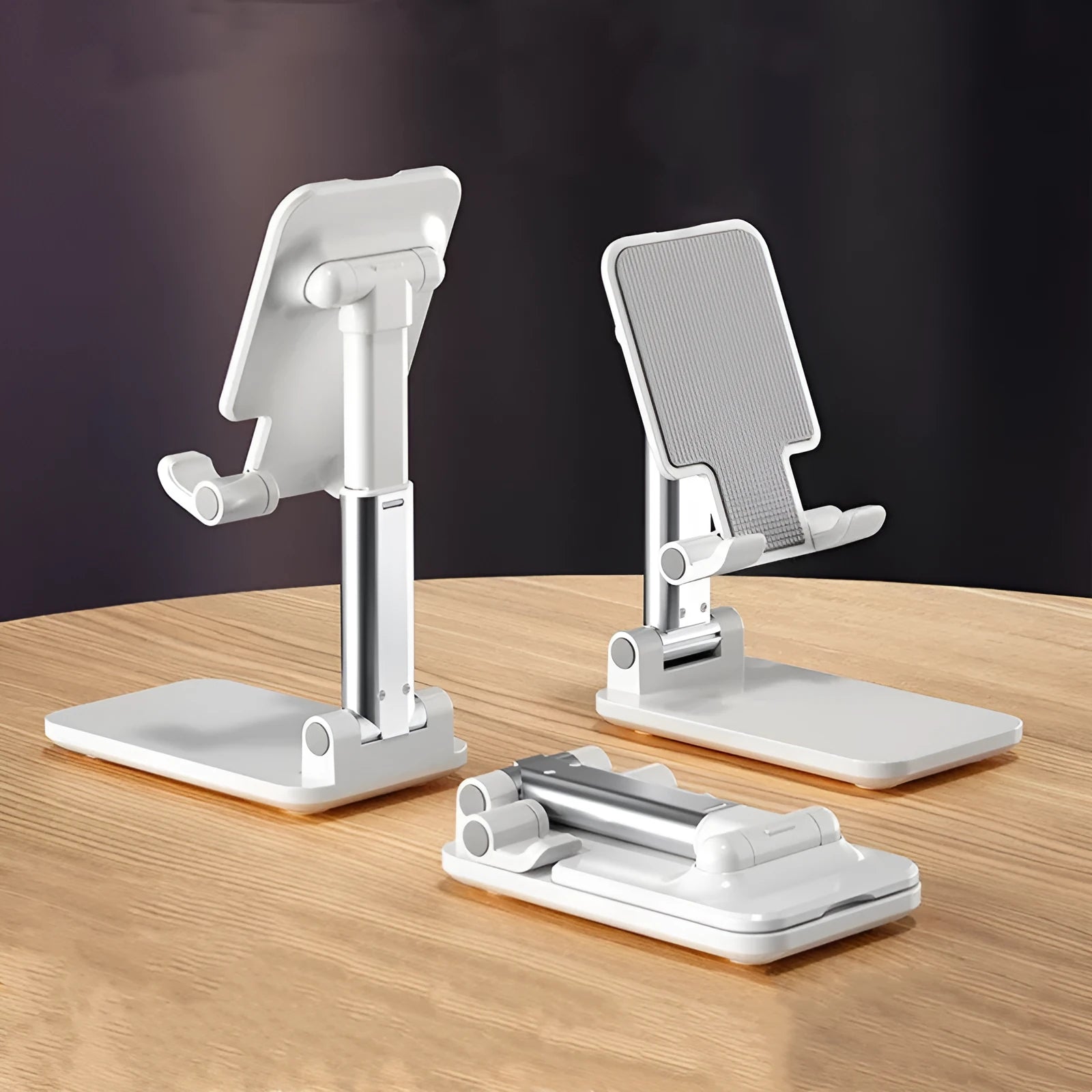 White folding telescopic mobile phone holder with silicone pad on a desktop, holding a smartphone at an angle.