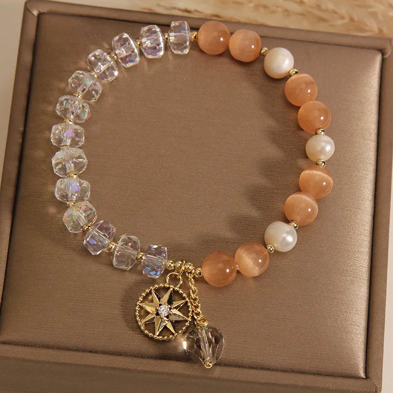 Gold-plated women's bracelet with an eight Awn star charm holding an inlaid orange opal crystal.