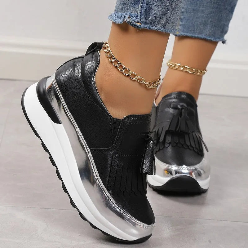 Women's black casual platform shoes with tassel detail and muffin wedge heel on a white background