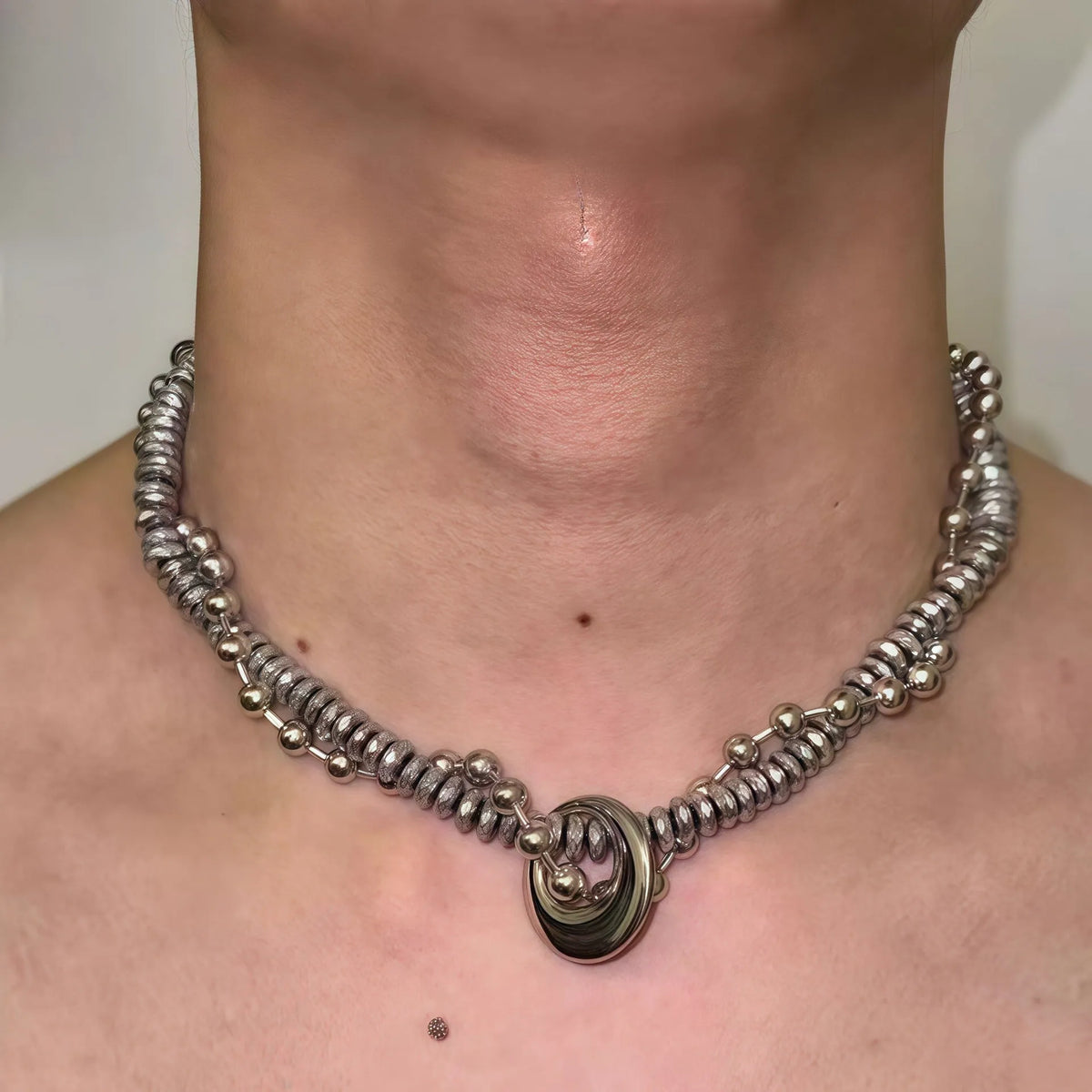 Silvery hand-woven titanium steel hip hop necklace with winding heavy industry chain texture on white background