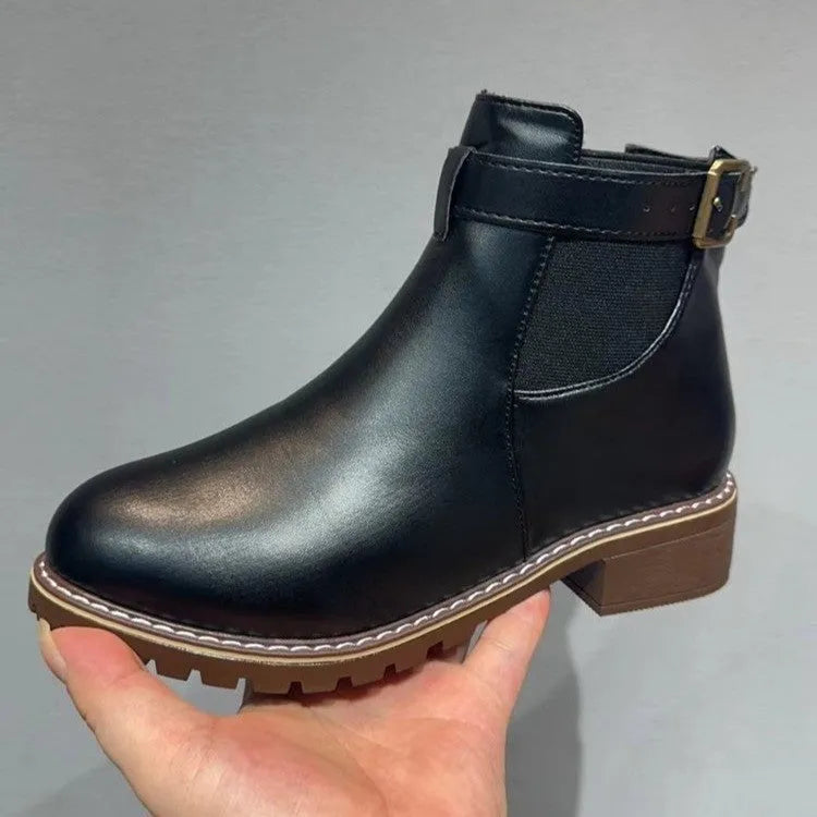 Black round toe women's ankle boot with a decorative metal belt buckle on the side.