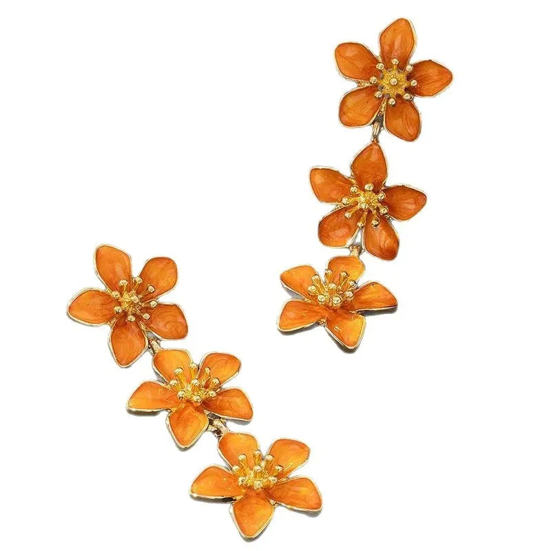 Oil dripping four petal flower earrings in orange resin on a white background