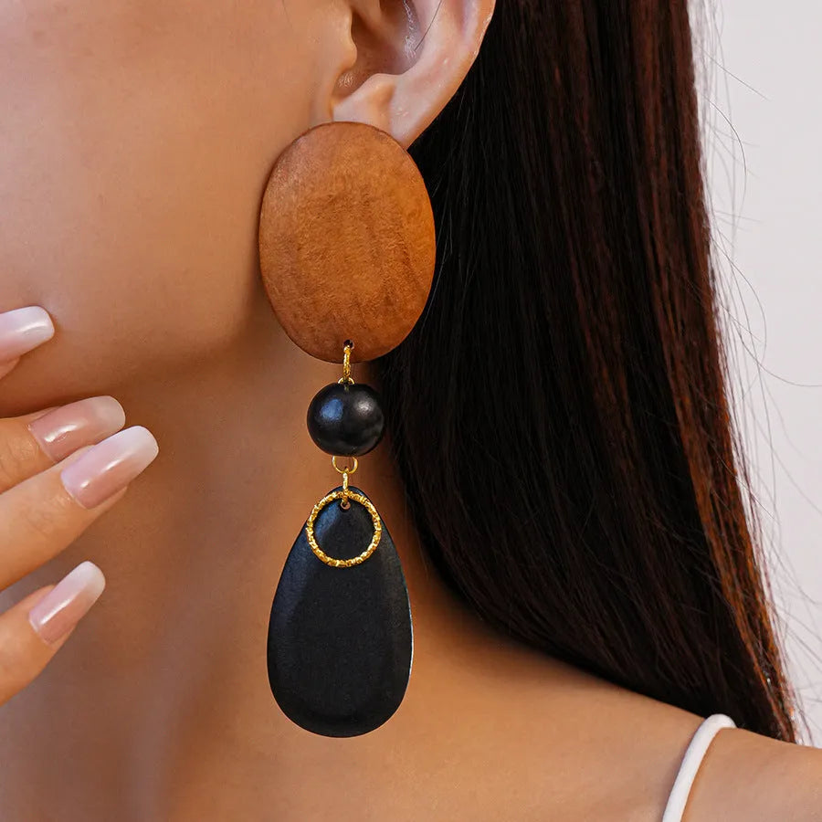 Wooden drop earrings with an ellipse shape in silver, brown, and black colours, showing manual craftsmanship.