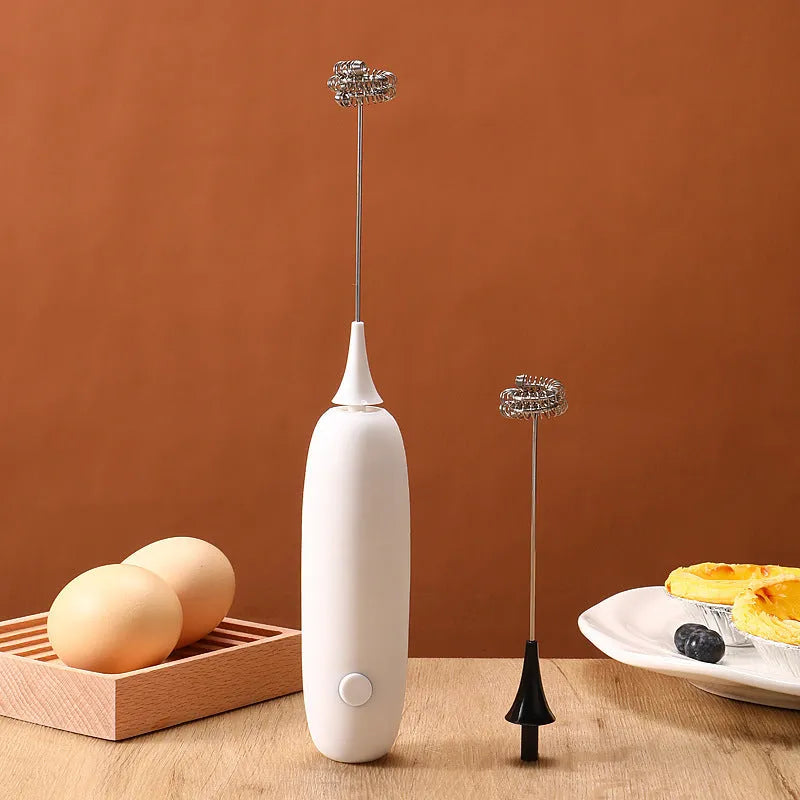 Handheld electric milk frother blender in black and white colour options on a kitchen counter.
