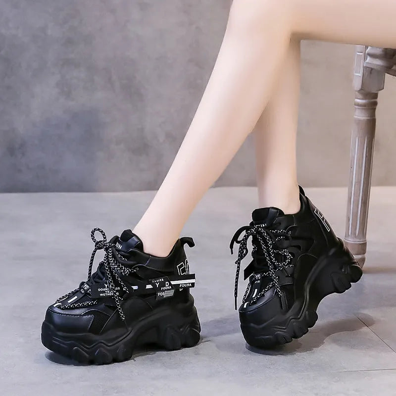 White women's low-top platform sports trainers with mesh panels and a black cross-strap on a rubber sole.