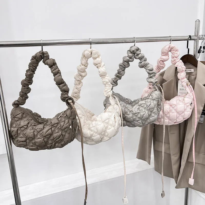 Women's light beige nylon cloud underarm messenger bag with a long adjustable shoulder strap.