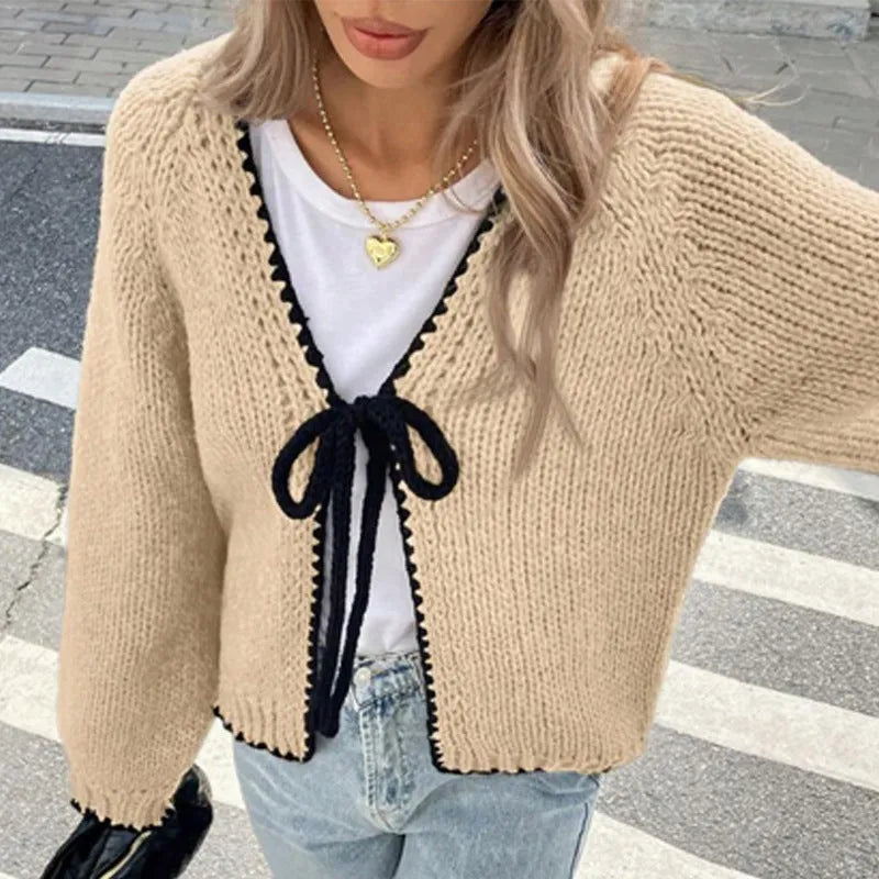 A solid colour loose-fit cardigan with long sleeves and small crochet flower details on the front.
