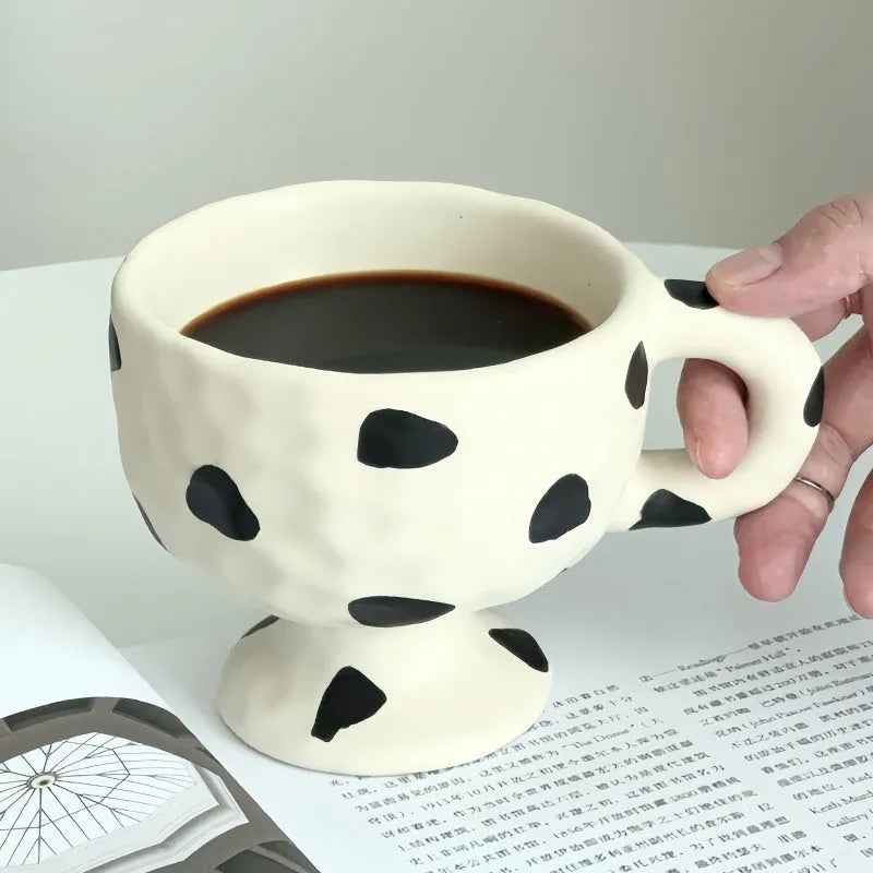 Hand-pinched irregular shaped solid colour ceramic mug on a table.