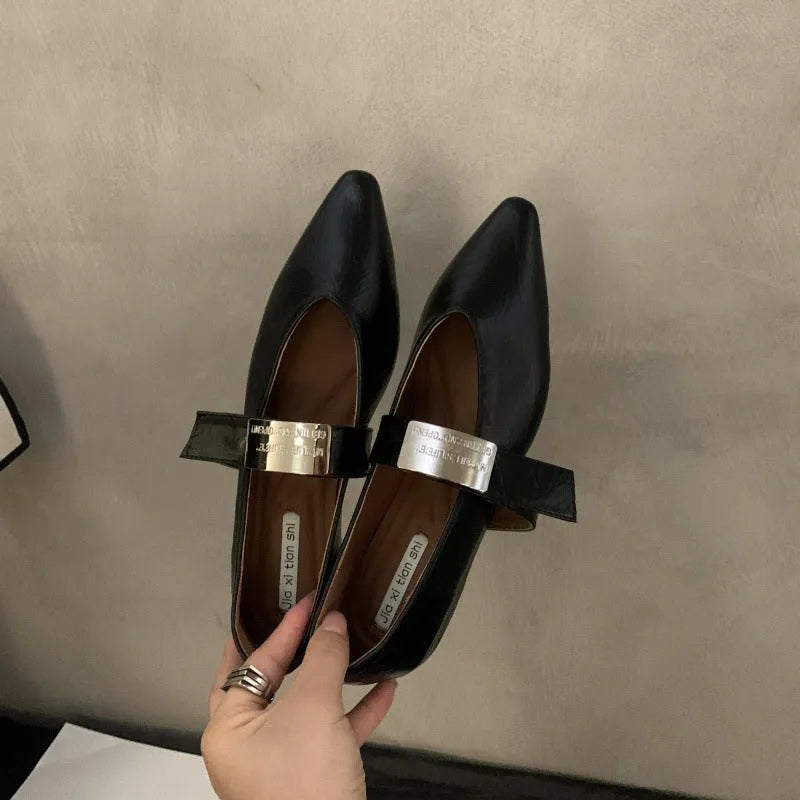 Women's black pointed toe Mary Jane buckle shoes with a low flat rubber sole.