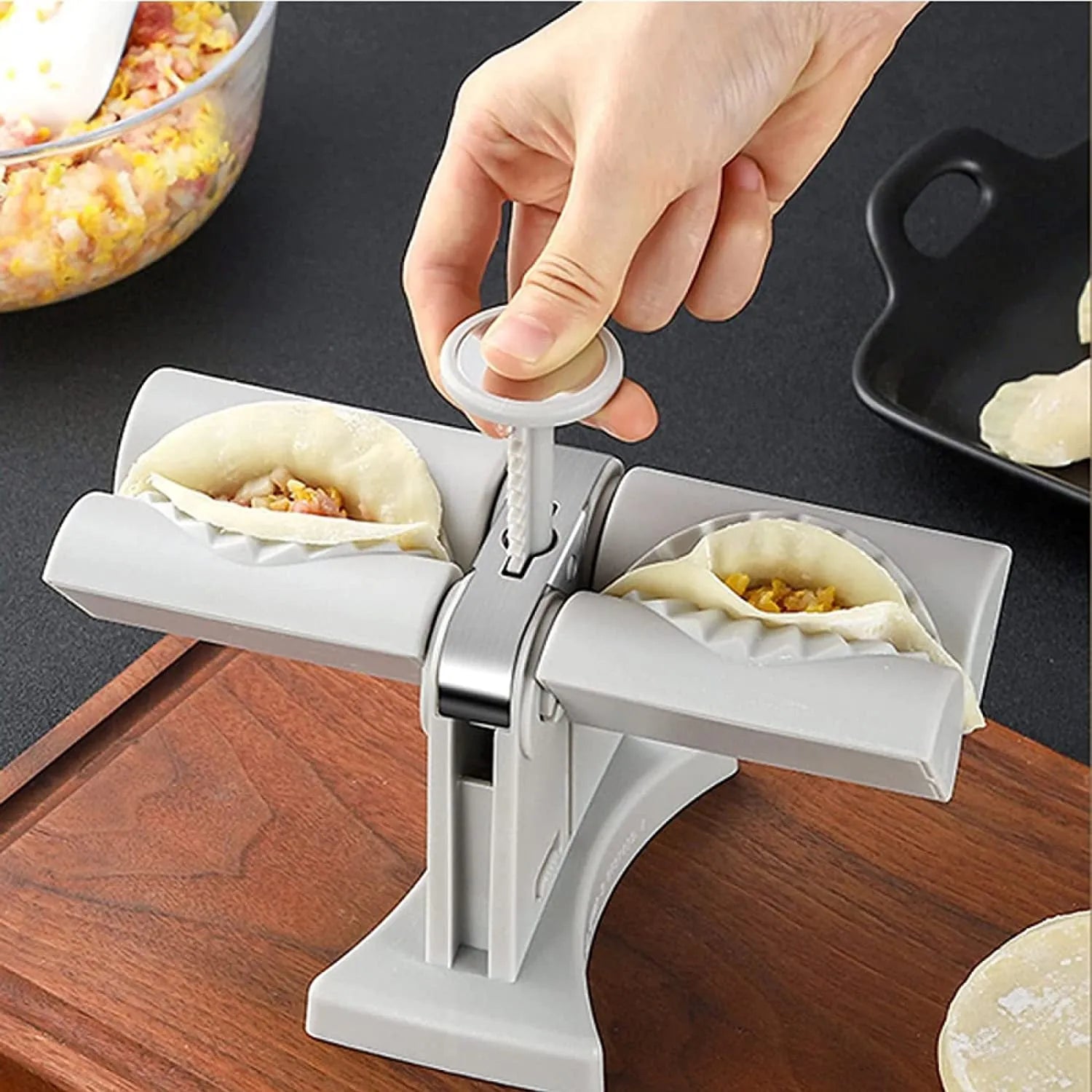 White double-head manual dumpling maker with anti-slip rubber base on a kitchen counter.