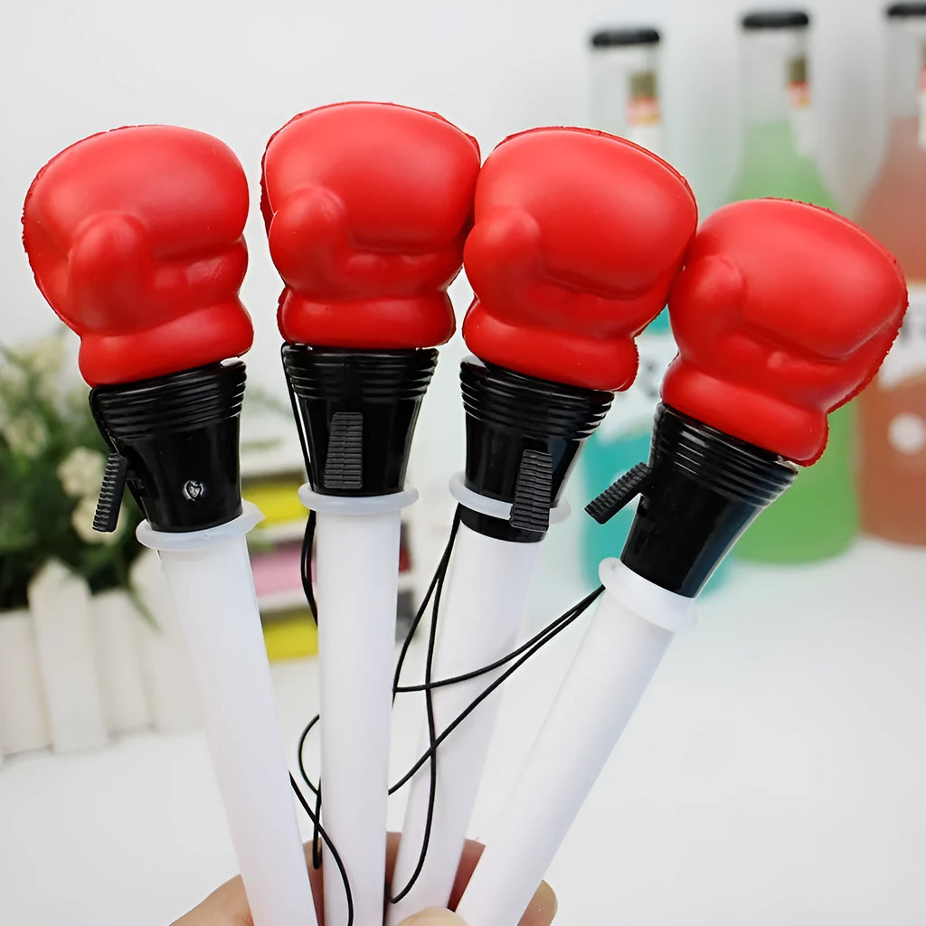Set of four black pressure relief pens with a boxing press ejection mechanism on a desk.
