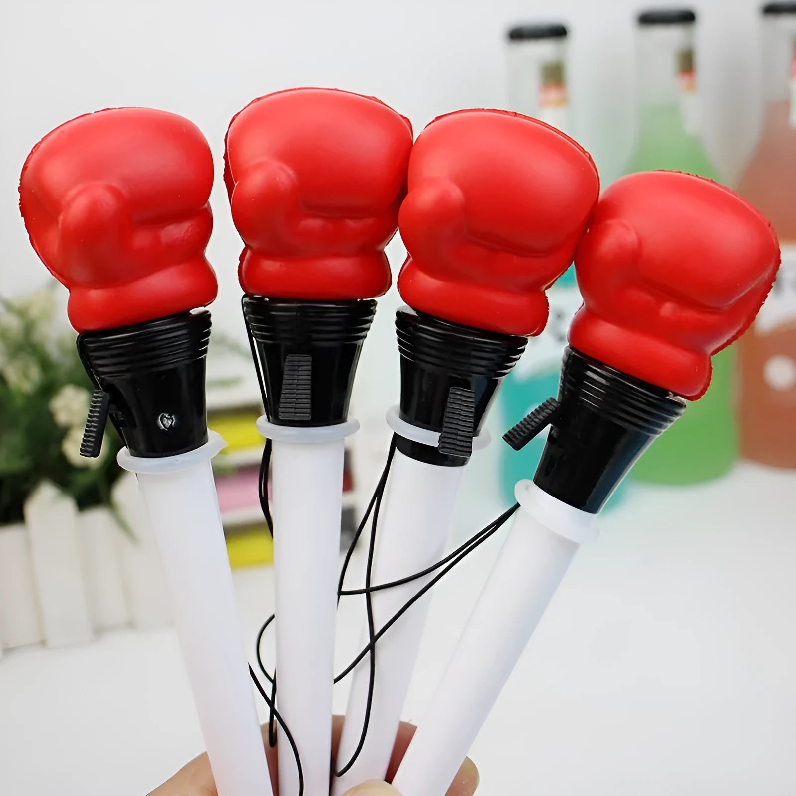 Set of four black pressure relief pens with a boxing press ejection mechanism on a desk.