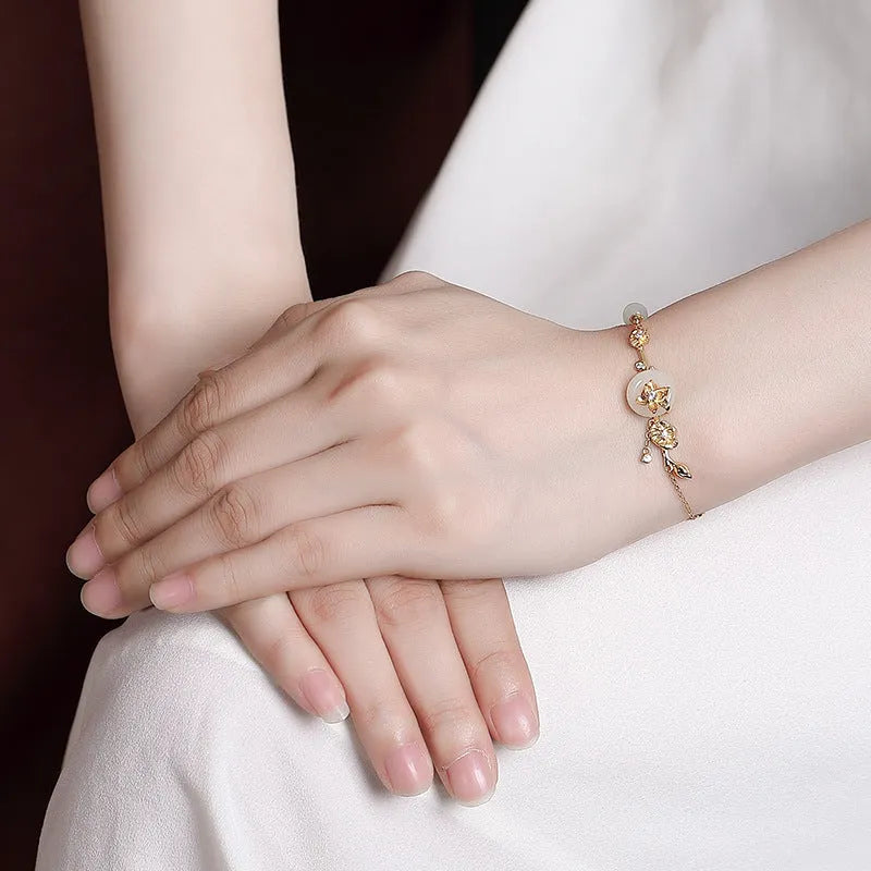 Women's 925 silver bracelet with inlaid Hetian jade centrepiece and ornate lotus peace buckle design.