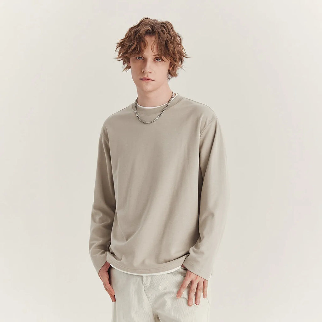 Man wearing a loose-fit long-sleeved cotton blend t-shirt in a solid colour, showing the round neck and casual style.