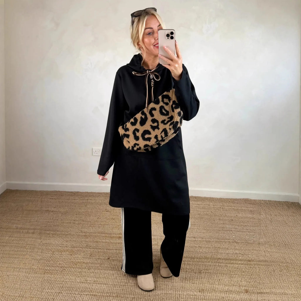 Woman wearing loose oversized knit hooded maxi dress in solid colour with front pockets, pullover style, black colour option