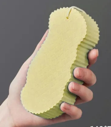White 3D fish scale pattern bath sponge with hang loop on a bathroom background.