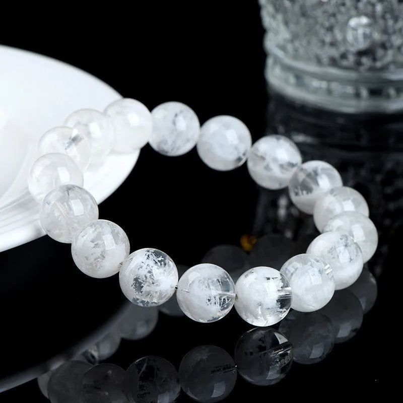 Women's natural blizzard snowflake round bead crystal bracelet with geometric design on a wrist.