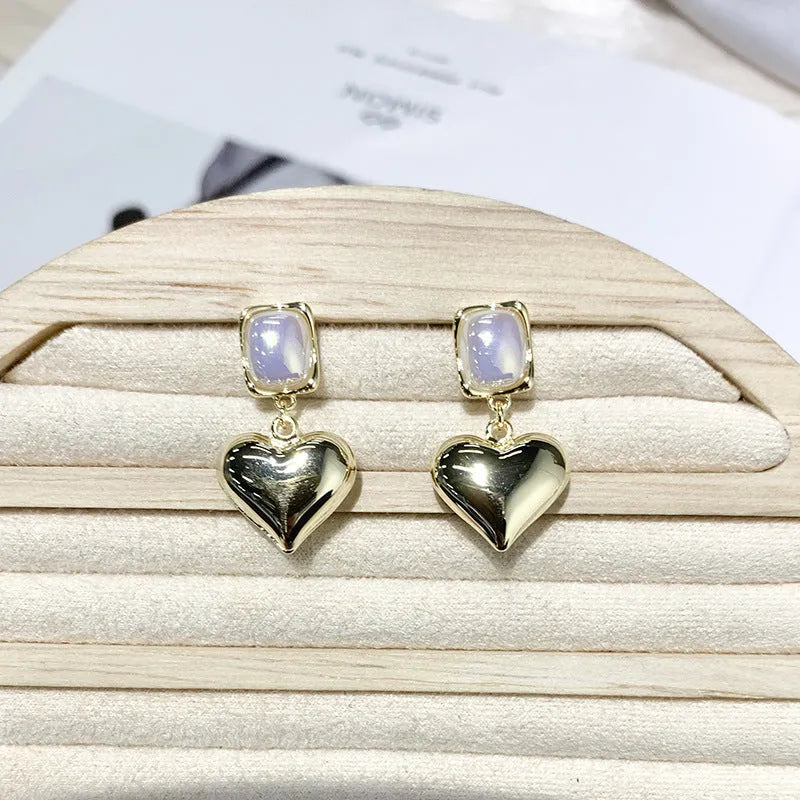 Small gold heart stud earrings with hypoallergenic metal finish on white background
