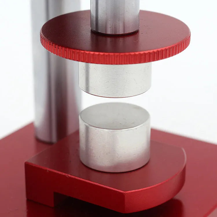 Watch repair spiral cap presser device with capsulator and set of 20 plastic moulds on a work surface.