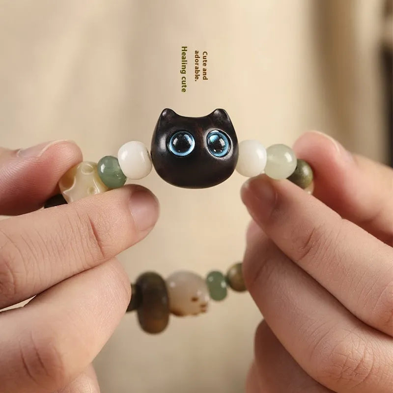 Beaded bracelet with a cube sugar cat's paw charm in guajacwood or ebony, featuring jade beads and a choice of yellow or blue eyes.