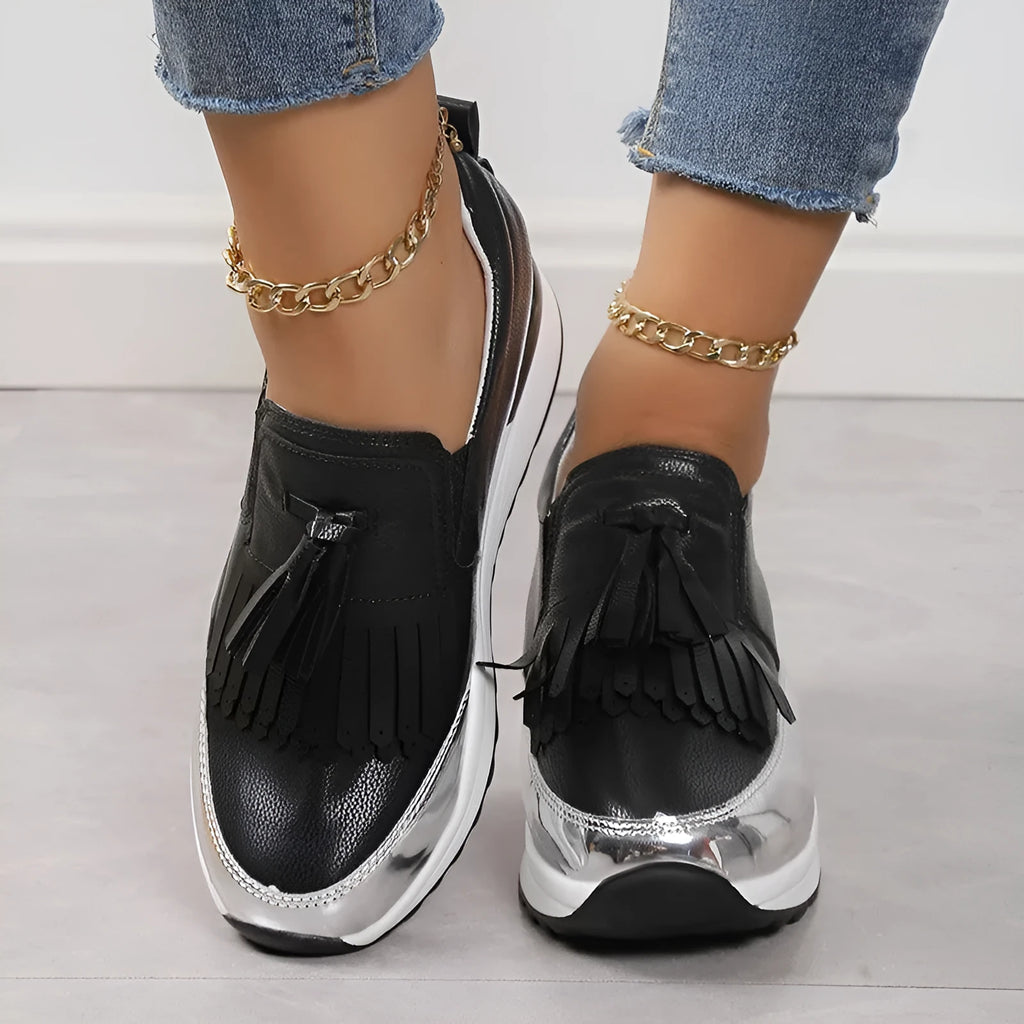 Women's black casual platform shoes with tassel detail and muffin wedge heel on a white background
