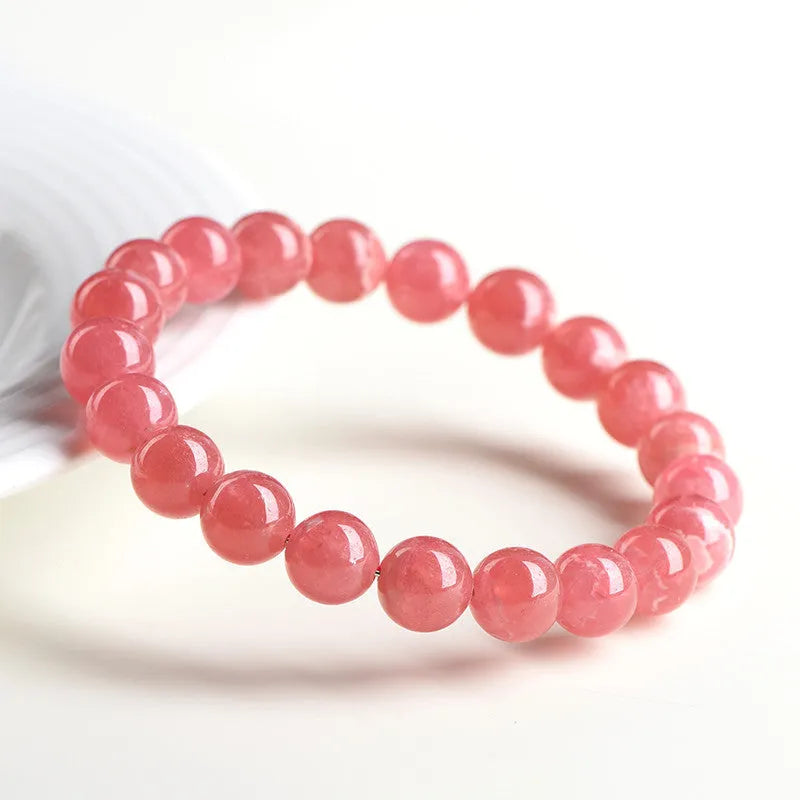 Women's geometric rhodochrosite crystal bracelet with a Longevity Lock centrepiece on a white background.