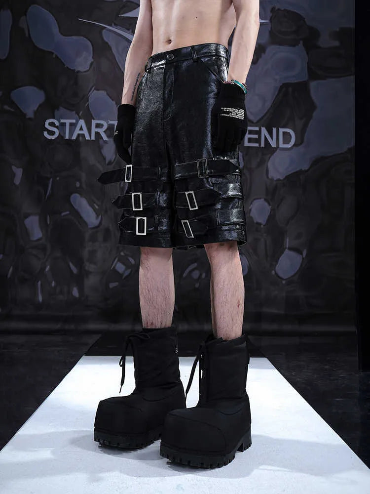 Black men's cropped PU leather shorts with ring detail on a hanger