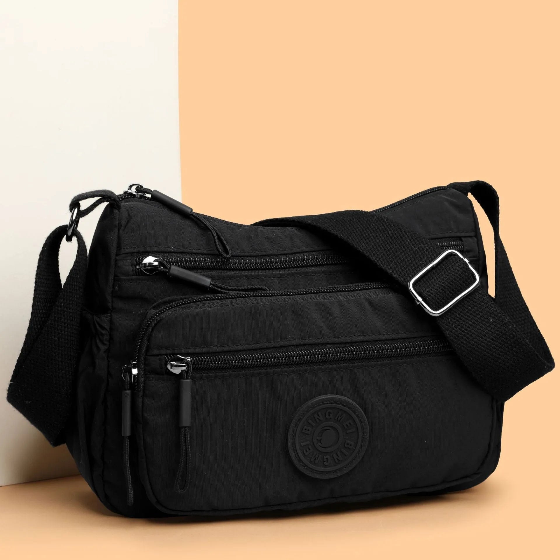 Soft water-repellent nylon crossbody bag in black with an outer pocket and zipped main compartment.