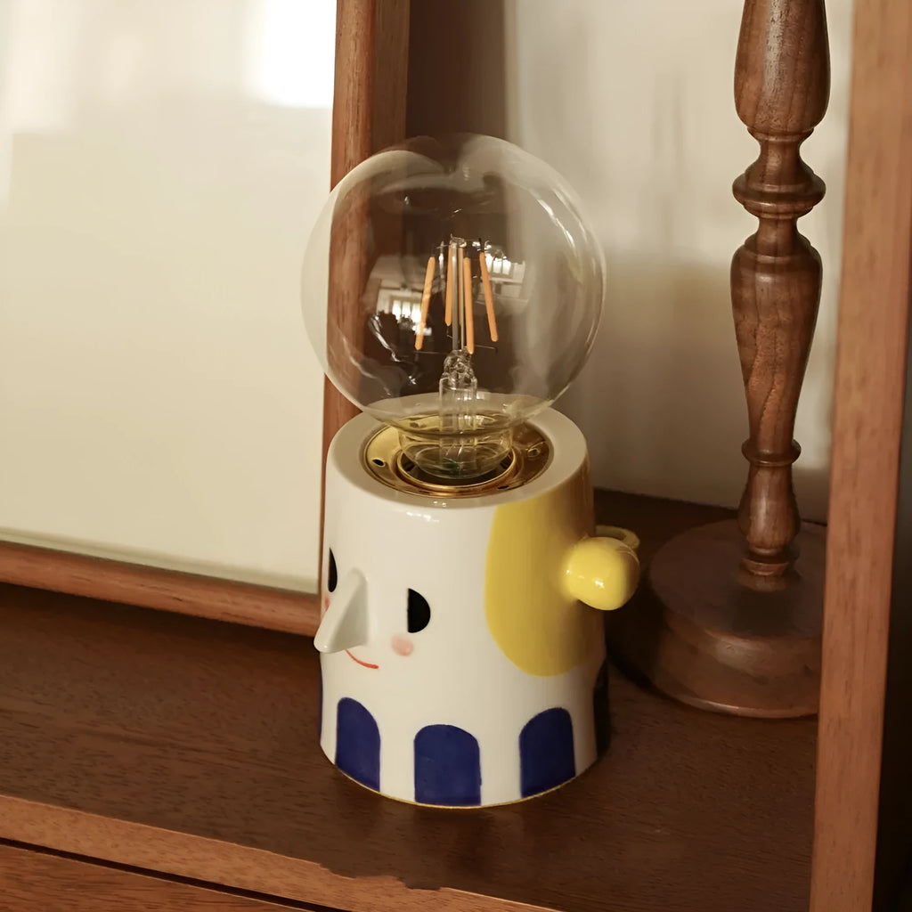 Off-white handmade ceramic table lamp with a rounded shape on a wooden surface.