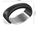 Stainless steel garlic press with coloured ergonomic handle on a kitchen counter.