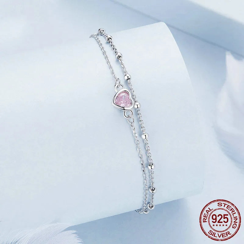 Close-up of a sweet girlish style sterling silver bracelet with a small heart pendant on an adjustable chain.