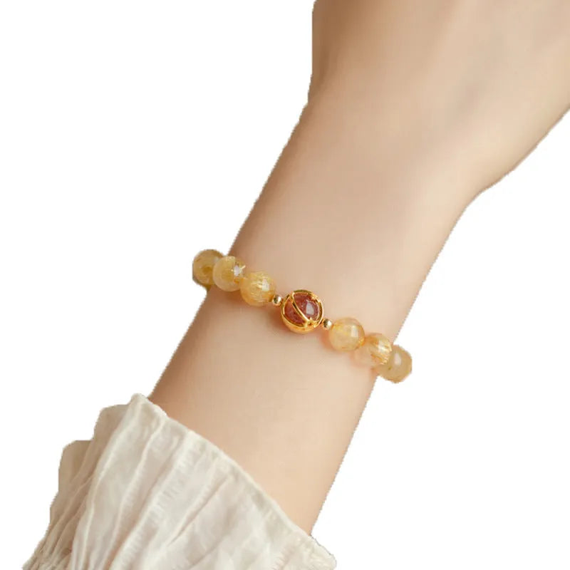 Citrine and gold rutilated quartz bracelet with diamond faceted beads on a wrist.