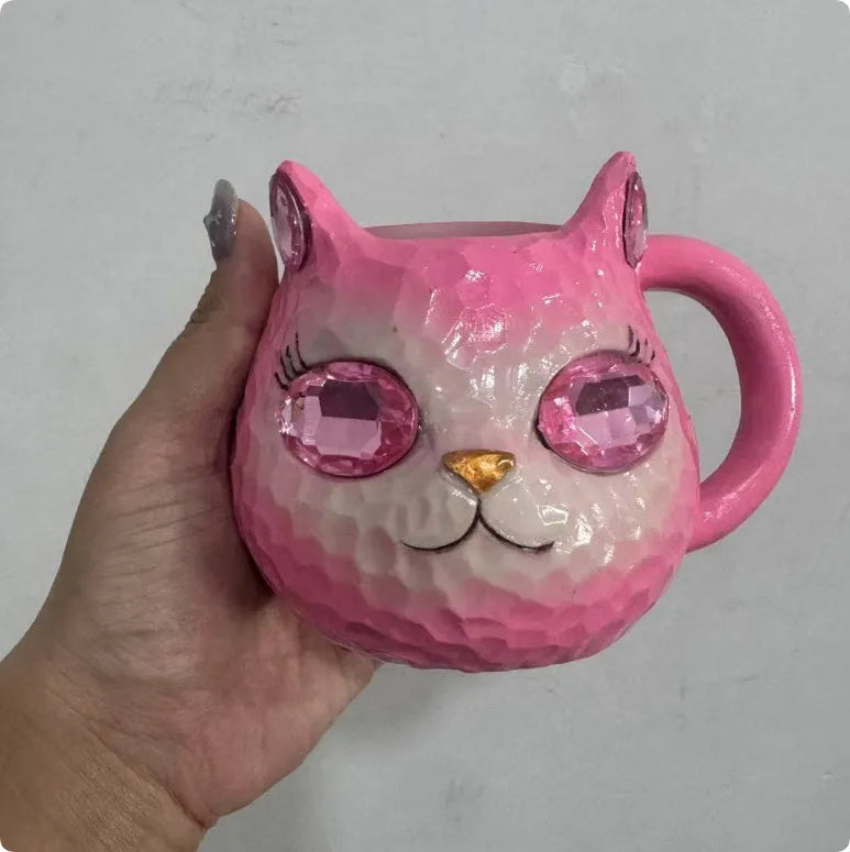 Small solid-colour resin cat cup craft figurine on a table, shown in purple, green, blue, and pink colour variants.