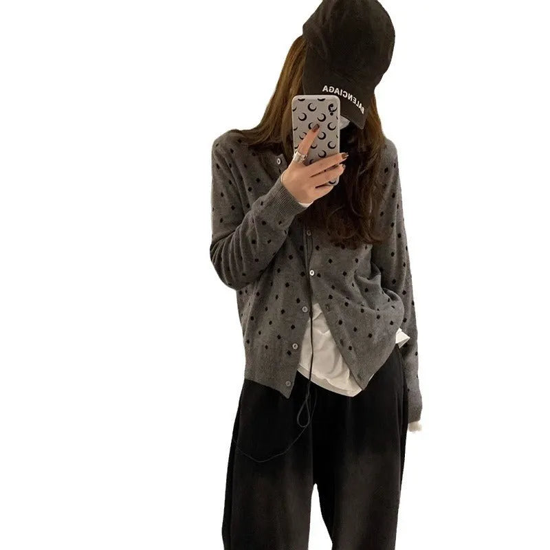 Grey dot pattern women's knitted cardigan with crochet flower detail on a hanger.