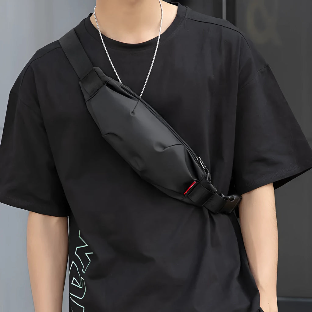 Black oxford cloth men's crossbody waist pack showing front zipper and strap.