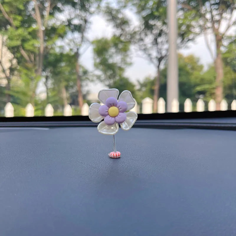 Small colourful plastic swing ornament for car dashboard, shown in multiple colour options.