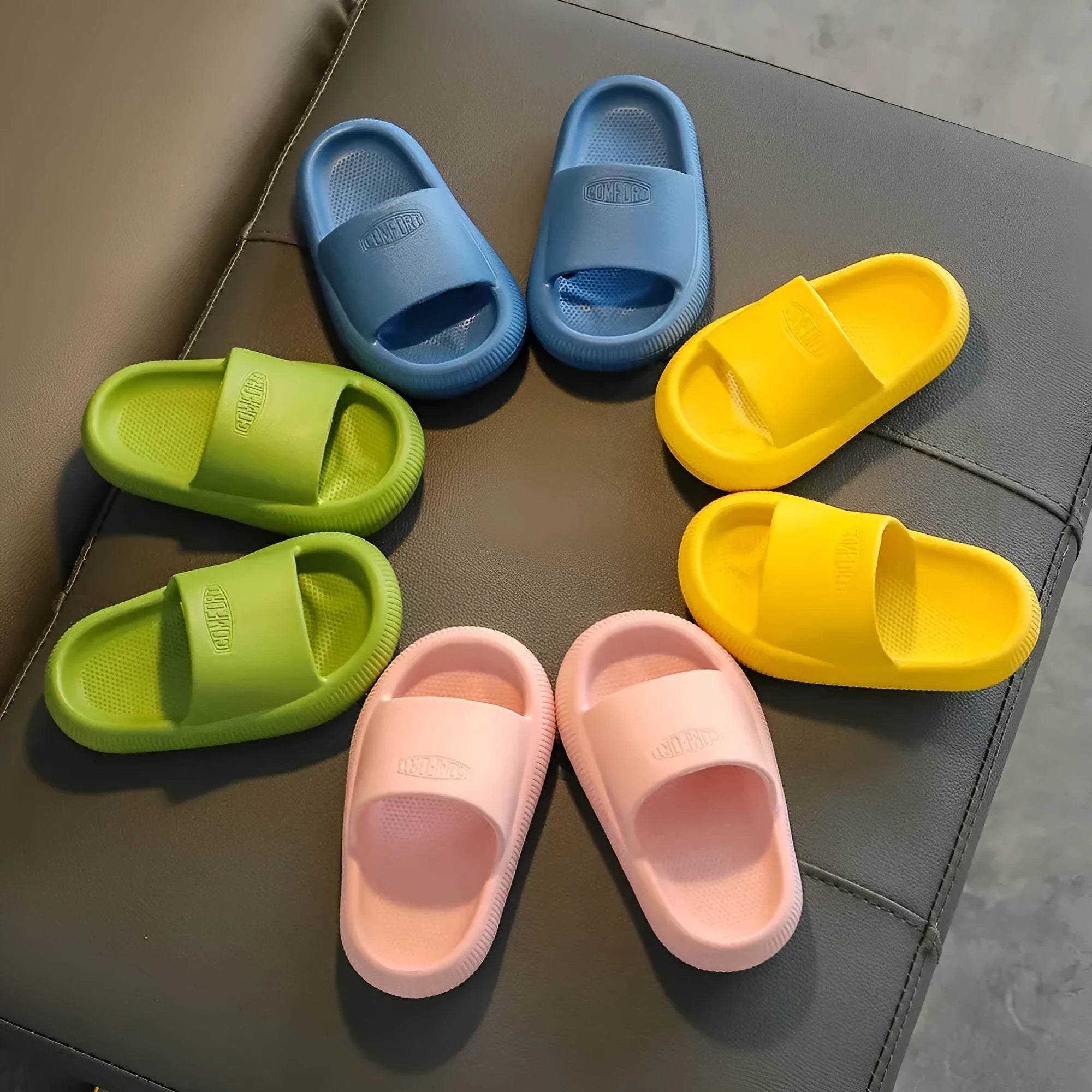 Colourful children's EVA slippers with textured non-slip sole, shown in blue, green, orange, pink, and yellow.