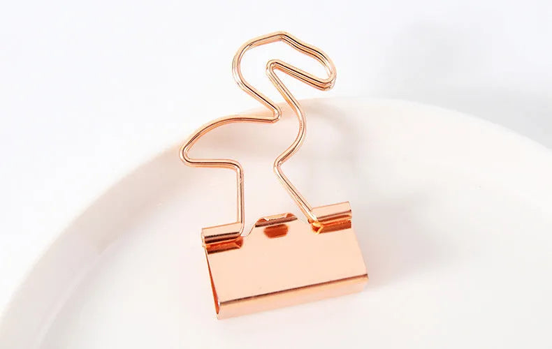 Gold metal alloy paper clip with decorative bow shape top on white background.