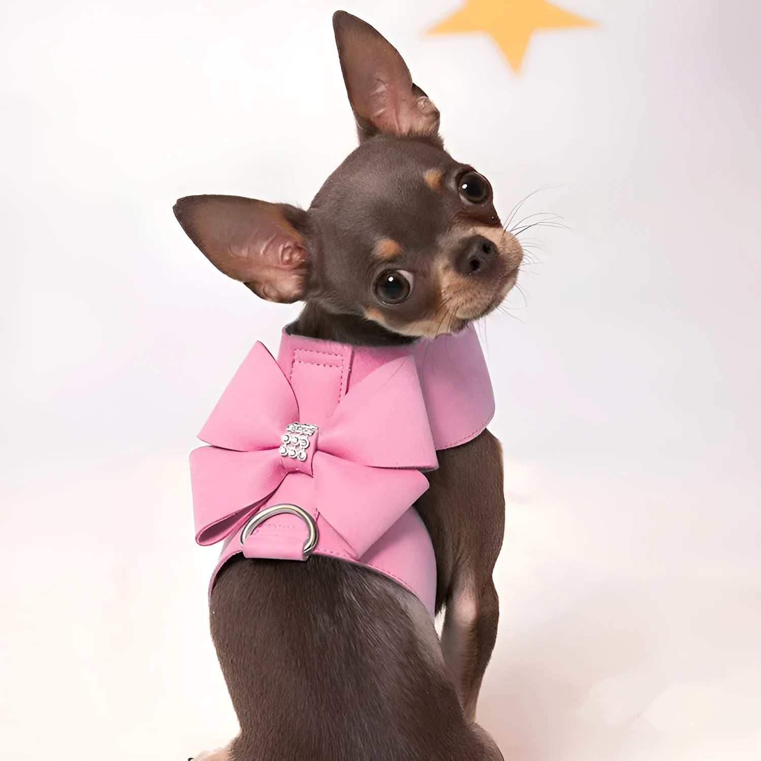A pink microfiber dog harness with a bowknot on the chest strap, shown on a small dog.