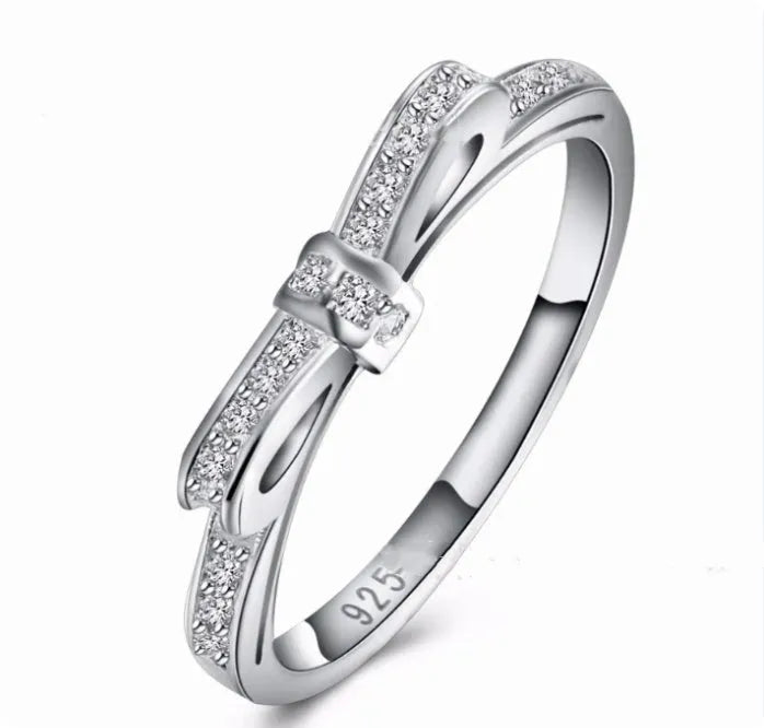 Close-up of a silver-tone bow-shaped ring with sparkling zircon crystal accents on a hand.