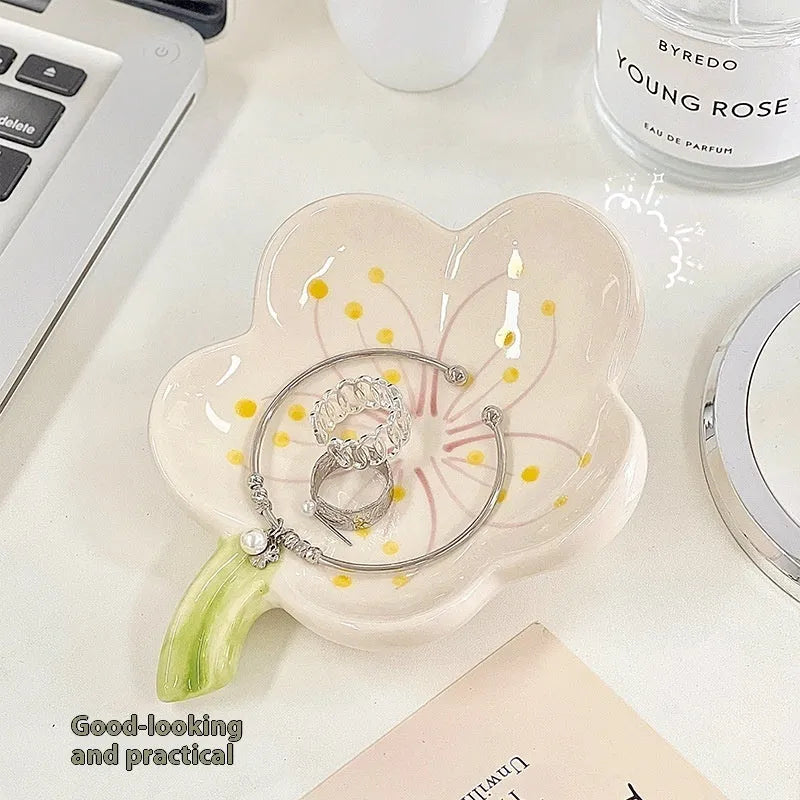 White porcelain decorative storage tray with a small built-in night light, holding jewellery on a bedside table