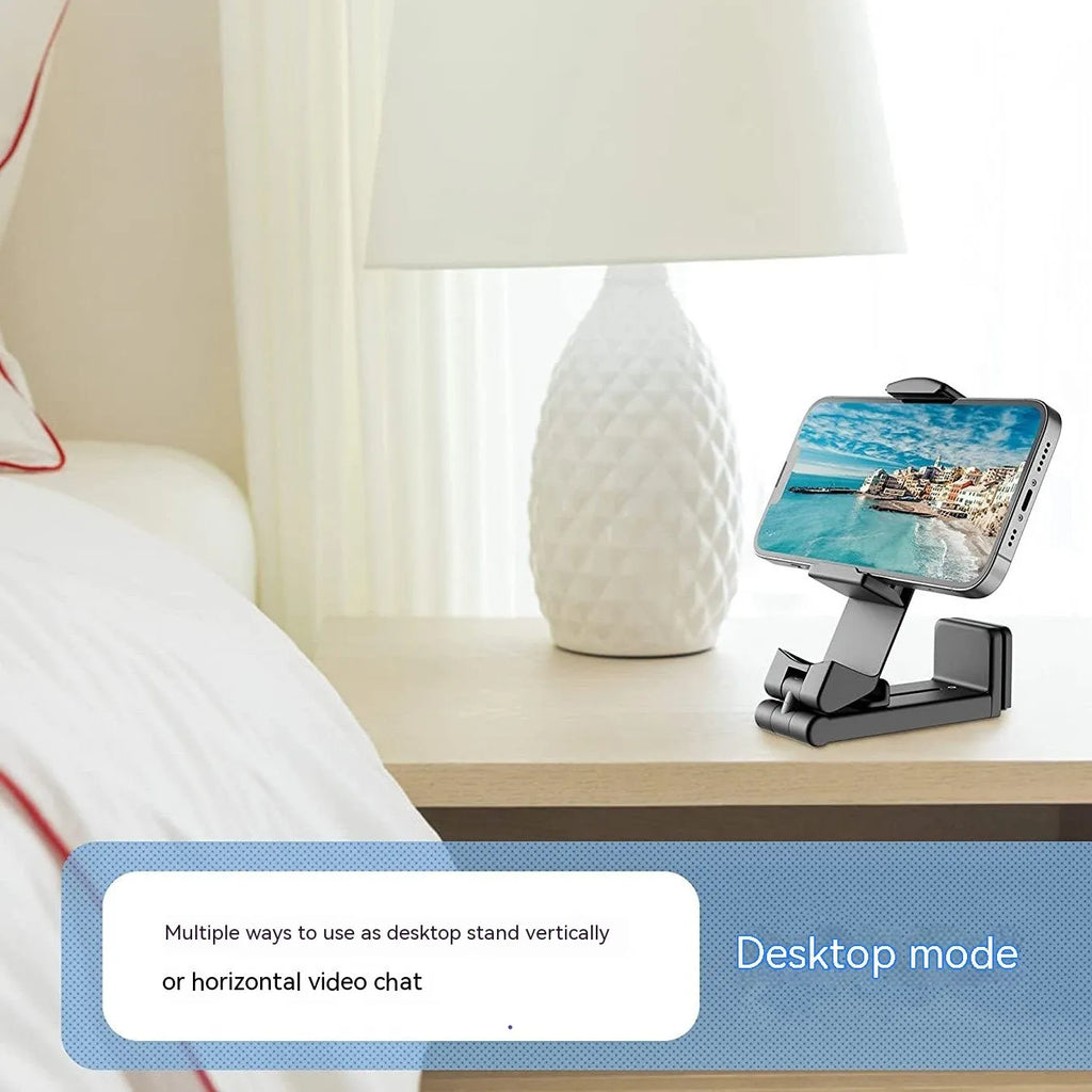 Foldable rotating universal phone holder in black on a desk next to a mobile phone.