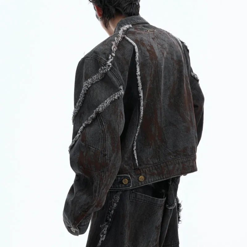 Black raw edge splash-dye distressed denim coat with padded shoulders and matching pants laid flat.