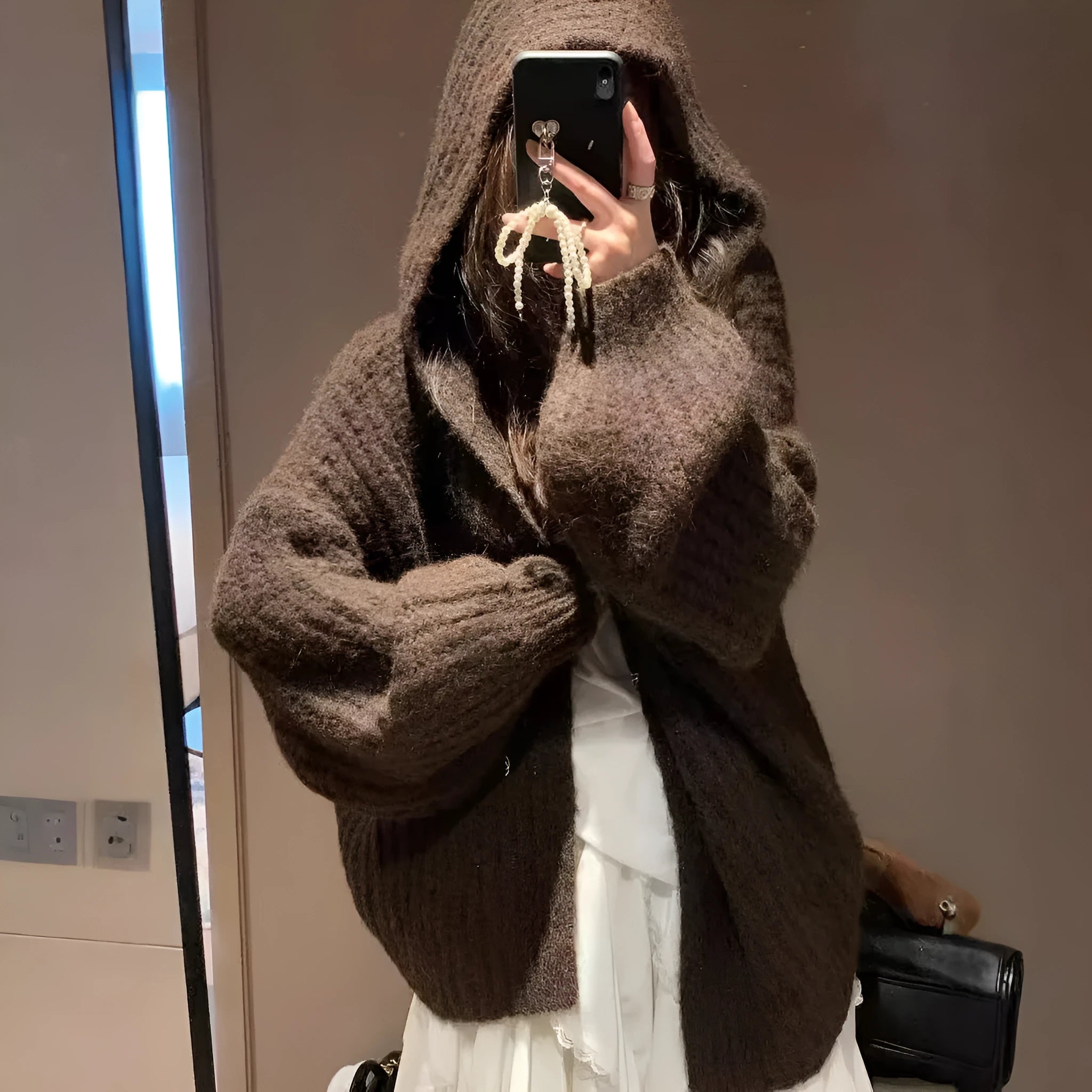 A woman wearing a loose-fit dark grey hooded cardigan made from thick acrylic blend fabric.